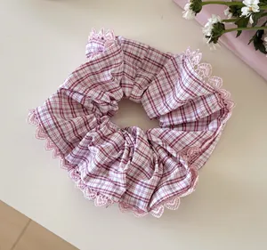 Close-up view showing the pink plaid pattern and delicate lace trim on this fabric scrunchie