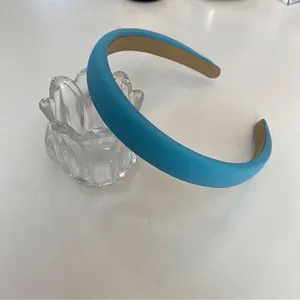 Primer plano de una diadema acolchada de esponja azul claro de 2 cm en soporte vidrio.