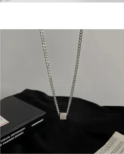 Detailed view of minimalist silver stainless steel cube pendant on a cuban curb chain