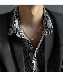 Close-up of minimalist titanium steel necklace with a geometric cube pendant.