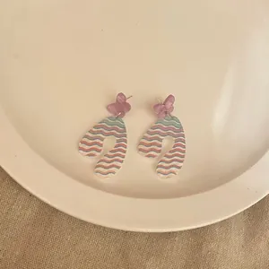 Close-up of cute acrylic butterfly earrings with colorful wavy pattern on white plate