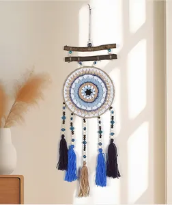 Atrapasueños bohemio hecho a mano con ojo turco y borlas azules sobre la pared