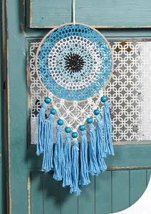 Detailed texture of bohemian hand-woven evil eye dreamcatcher with blue cotton tassels.
