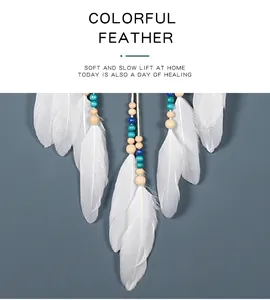 Close-up detail of white feathers and blue beads on a bohemian dreamcatcher pendant