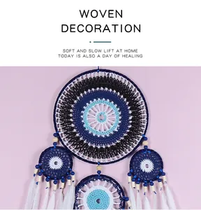 Détail rapproché d'un attrape-rêves Evil Eye tissé main avec perles bleues et plumes blanches.