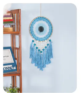 Detailed view of a handmade Bohemian evil eye dreamcatcher with blue tassels on wall