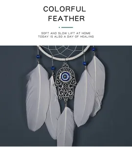Detail van witte veren en de Hamsa-hand hanger met een blauw boos oog symbool.