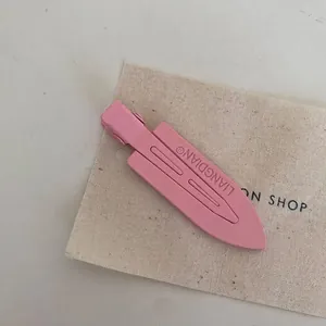 Close-up of a matte peach pink metal hair clip presented on a canvas display card
