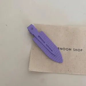 Detailed close-up of a purple ribbed metal alligator hair clip on a canvas background