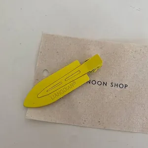 Detail of a macaron yellow metal hair clip with embossed brand logo on fabric