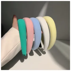 Detailed view showing a variety of pastel candy-colored padded sponge headbands held in hand