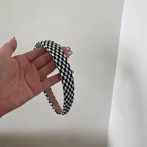 Primo piano di un elegante cerchietto largo 2 cm con motivo a scacchi bianco e nero