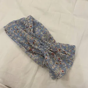 Detalle de manguitos de protección solar en gasa con flores azules y puños elásticos.