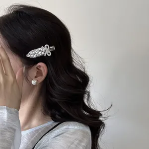 Nahaufnahme einer luxuriösen Haarspange mit Perlen und Strassschleife im schwarzen Haar.