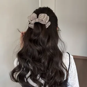 Vista trasera de una mujer con un lazo de organza beige en su pelo largo ondulado