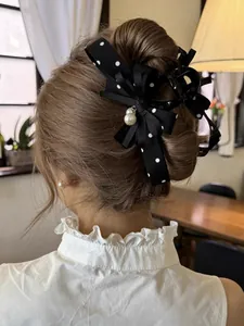 Vista dettagliata di un'elegante pinza per capelli con fiocco nero a pois nel bun