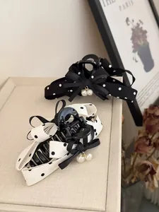Dettaglio di fermagli per capelli con fiocco a pois e ciondoli di perle su vassoio