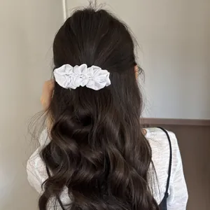 Detailed view of white pleated pearl banana clip styled on long wavy hair
