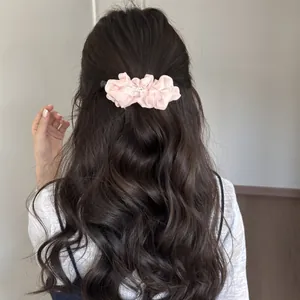 Back view of elegant pink pleated pearl banana clip styled in a wavy ponytail.