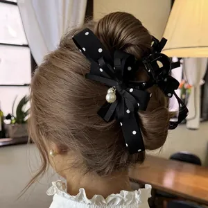 Elegante molletta per capelli con fiocco a pois neri e ciondoli di perle nell'acconciatura