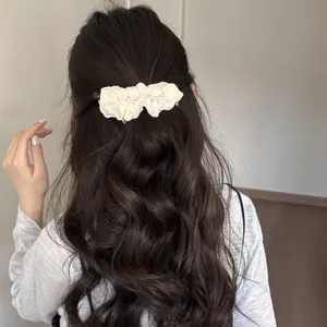 Macro detail view of elegant ruffled pearl banana clip worn in styled wavy brown hair