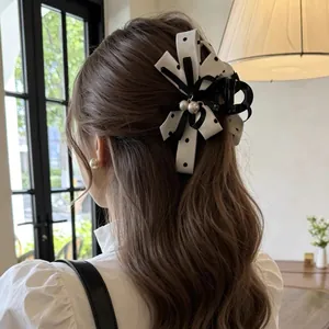 Elegante molletta a fiocco a pois neri e bianchi indossata su lunghi capelli ondulati