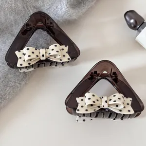 Gedetailleerde weergave van bruine haarklemmen met polkadotstrik op een grijze gebreide achtergrond