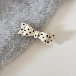 Detailopname van een crèmekleurige haarstrik met stippen op grijze pluizige stof