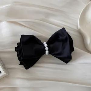 Detailed close-up of a vintage black satin hair clip with elegant pearl center embellishment.
