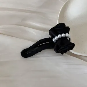 Detailed view of a vintage black satin bow hair clip featuring elegant white pearl beads