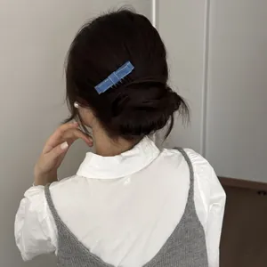 Close-up detail of a blue denim bow hair comb clip styled in a soft bun hairstyle