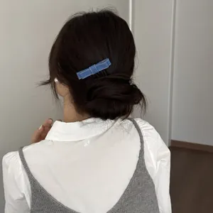 Detailed back view of an elegant blue denim bow hair clip styled on a low hair bun