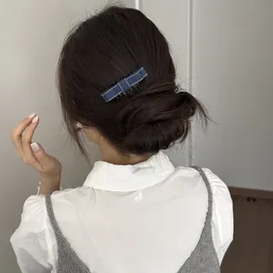 Detailed macro view showing a blue denim bow hair clip worn in a low bun hairstyle