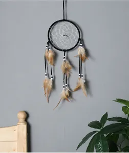 Gros plan d'un attrape-rêves fait main avec des plumes sur un mur gris minimaliste