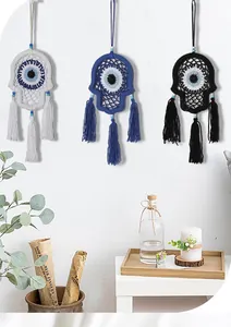 Three hand-woven Hamsa Evil Eye wall hangings in white, blue, and black in lifestyle setting.