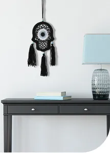 Handwoven black Hamsa hand evil eye wall hanging with tassels in a modern room setting