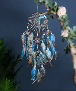 Atrapasueños turquesa hecho a mano con plumas azules y marrones para decoración de pared.
