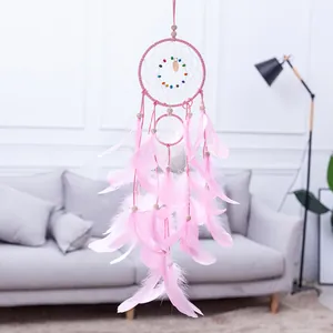 Detailopname van roze dromenvanger met delicate veren en gekleurde kralen in kamer.