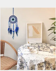 Acchiappasogni blu Evil Eye con piume appeso su una parete domestica minimalista