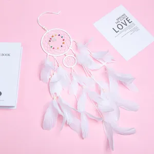 Elegante witte boheemse dromenvanger met zachte veren en kralen op roze achtergrond