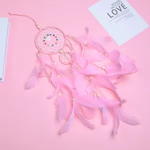 Detail van de delicate roze veren en kralenaccenten van de hangende dromenvanger.