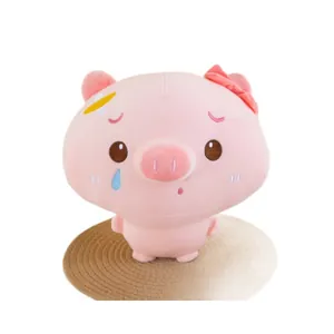 Adorable pink crying pig plush toy with bow and bandage accessory on a woven mat