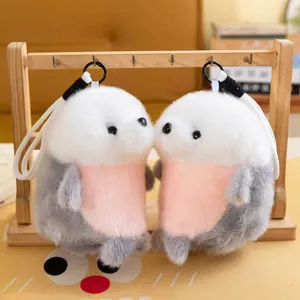 Close-up detail of two fluffy seal plush keychains hanging on a wooden stand