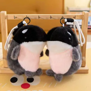Detailed view of two cute fuzzy orca plush keychains with pink bellies and white spots.