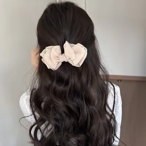 Vista trasera que muestra un elegante clip de lazo de organza en el pelo ondulado