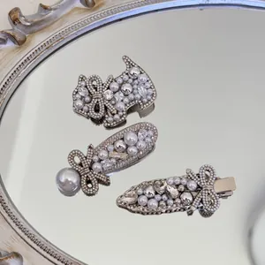Elegante Haarklammern mit Perlen und Strass auf einem dekorativen Vintage-Spiegel