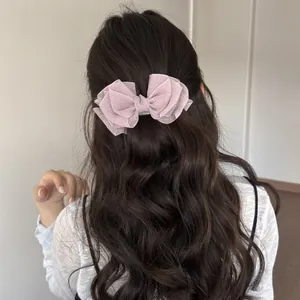 Primer plano de una pinza para el pelo con lazo de organza rosa en cabello ondulado