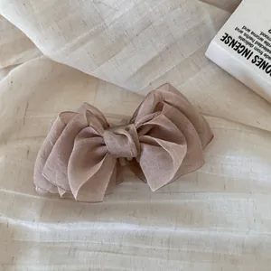 Primer plano de una delicada pinza de pelo con lazo de organza multicapa color moka.
