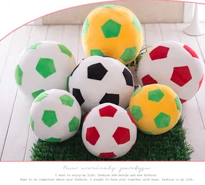 Colorful soccer ball plush toys arranged on decorative artificial grass.