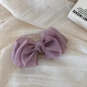 Vista detallada del lazo de organza violeta multicapa sobre un fondo de lino suave